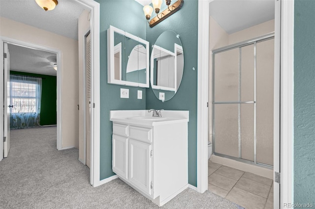 bathroom with tile patterned floors, vanity, a shower with door, and a textured ceiling