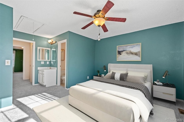 carpeted bedroom with ensuite bath, ceiling fan, sink, and a textured ceiling