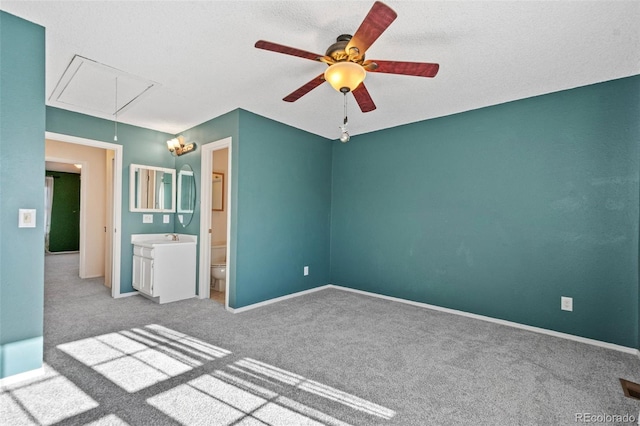 unfurnished bedroom featuring sink, ceiling fan, a textured ceiling, connected bathroom, and light colored carpet