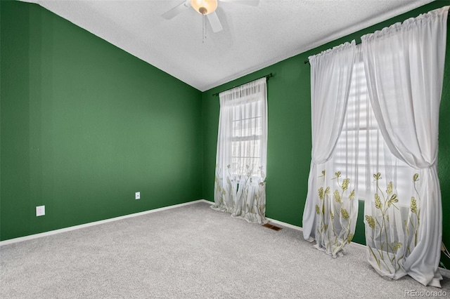 unfurnished room featuring carpet flooring, ceiling fan, vaulted ceiling, and a textured ceiling