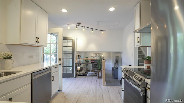 13833 W 68th Ave, Arvada, CO 80004 - kitchen featuring appliances with stainless steel finishes, light countertops, white cabinetry, light wood-style flooring, and decorative backsplash