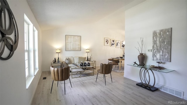 13833 W 68th Ave, Arvada, CO 80004 - living area featuring wood finished floors, healthy amount of natural light, lofted ceiling, and baseboards
