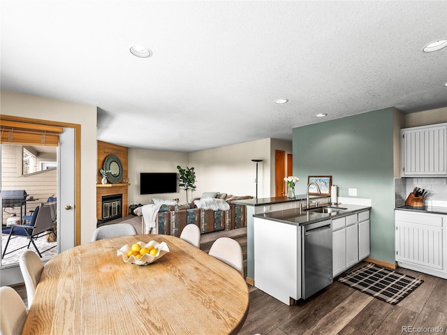 kitchen with sink, dishwasher, white cabinetry, dark hardwood / wood-style flooring, and decorative backsplash