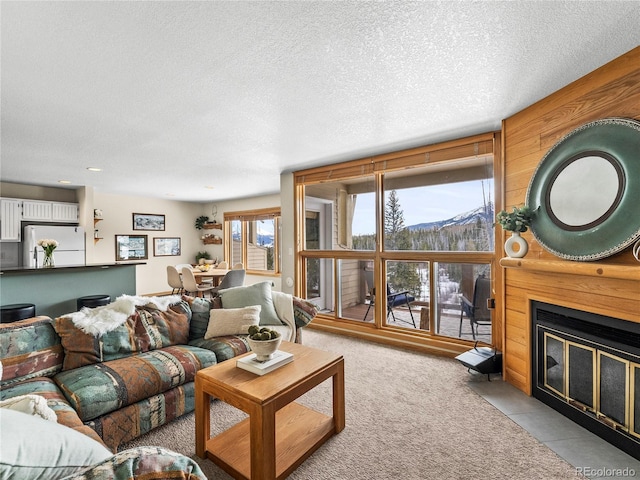 living room with a mountain view, light colored carpet, and a textured ceiling