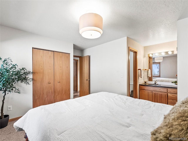 carpeted bedroom with sink, a closet, and a textured ceiling