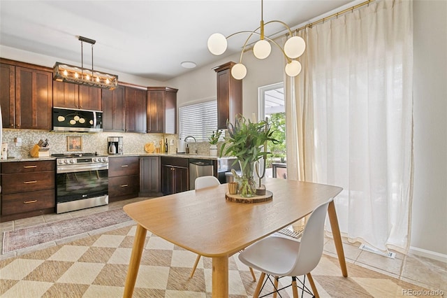 3618 Boot Spur Ct, Colorado Springs, CO 80922 - kitchen featuring appliances with stainless steel finishes, decorative backsplash, dark brown cabinetry, a sink, and light tile patterned floors