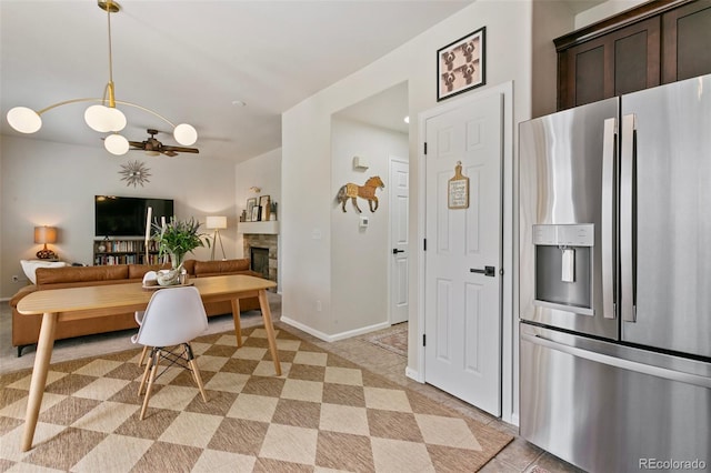 3618 Boot Spur Ct, Colorado Springs, CO 80922 - kitchen featuring stainless steel fridge, dark brown cabinetry, a fireplace, pendant lighting, and light tile patterned floors