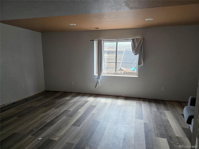 spare room featuring wood finished floors, a textured ceiling, and recessed lighting