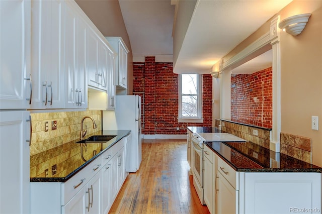 kitchen with white appliances, brick wall, sink, and white cabinets