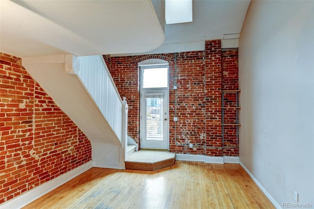 bonus room with brick wall and light wood-type flooring