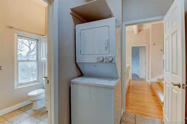 clothes washing area with light tile patterned floors and stacked washing maching and dryer