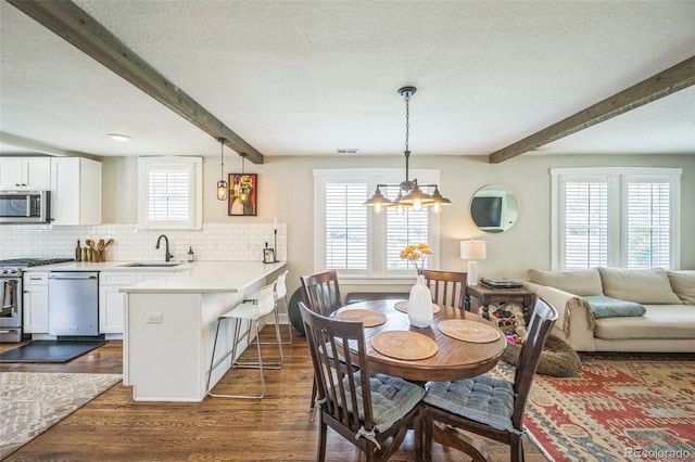 7340 W 32nd Ave, Wheat Ridge, CO 80033 - dining space with beamed ceiling, a chandelier, dark wood finished floors, and a textured ceiling