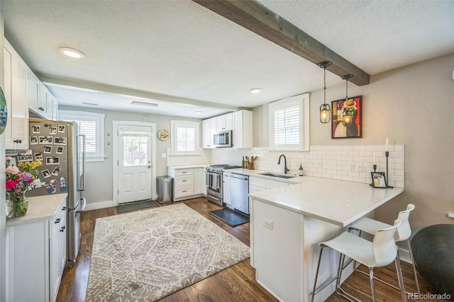 7340 W 32nd Ave, Wheat Ridge, CO 80033 - kitchen with appliances with stainless steel finishes, a textured ceiling, a peninsula, backsplash, and white cabinets