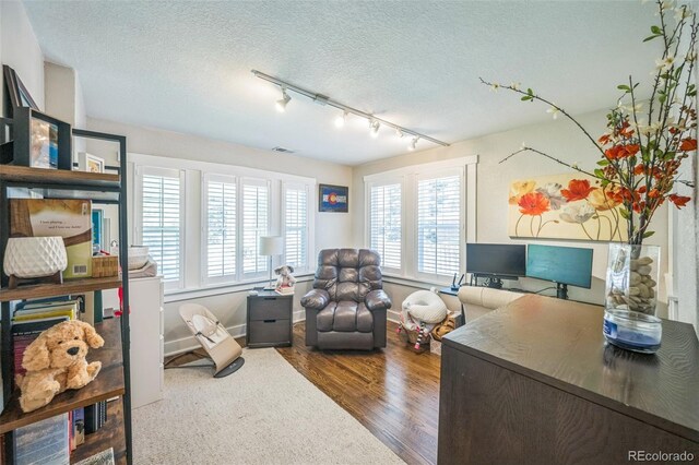 7340 W 32nd Ave, Wheat Ridge, CO 80033 - home office featuring rail lighting, wood finished floors, healthy amount of natural light, and a textured ceiling