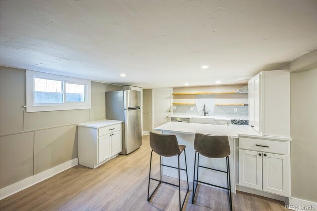 7340 W 32nd Ave, Wheat Ridge, CO 80033 - kitchen with stainless steel appliances, open shelves, a peninsula, white cabinets, and light wood-style flooring