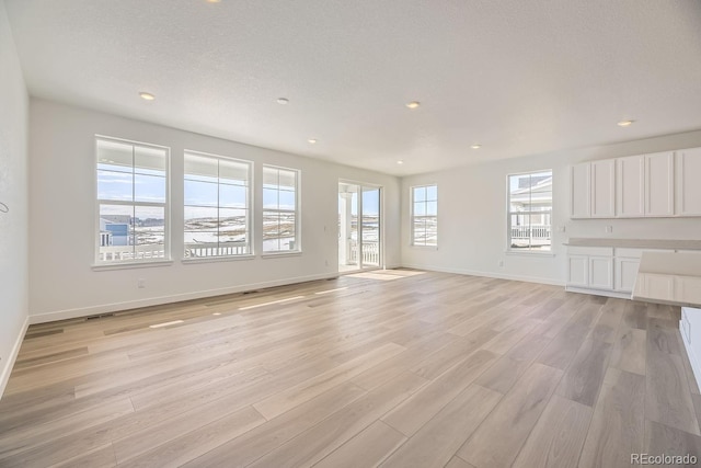 unfurnished living room with a textured ceiling and light wood-type flooring