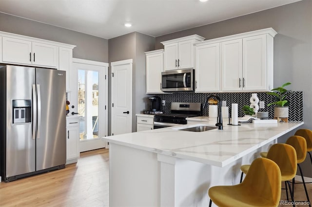 22203 E 6th Pl, Aurora, CO 80018 - kitchen featuring stainless steel appliances, a peninsula, a sink, decorative backsplash, and white cabinets
