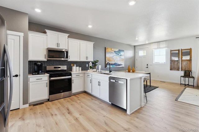 22203 E 6th Pl, Aurora, CO 80018 - kitchen featuring stainless steel appliances, a sink, a peninsula, light wood-style floors, and recessed lighting