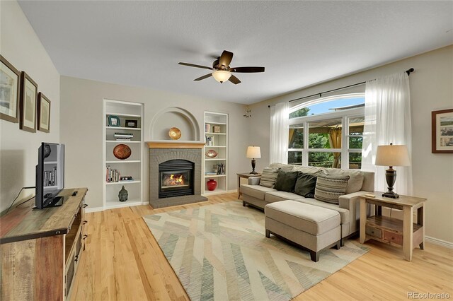 20530 Parker Vista Cir, Parker, CO 80138 - living room with light wood-style flooring, a ceiling fan, a brick fireplace, and baseboards
