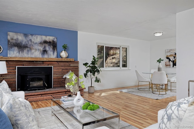 living room featuring a fireplace with raised hearth and wood finished floors