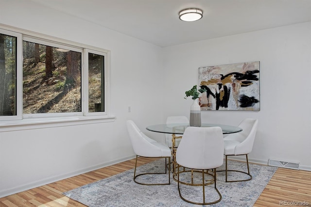 dining room with wood finished floors, baseboards, and visible vents