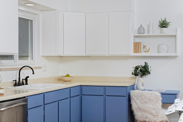 kitchen with blue cabinets, a sink, stainless steel dishwasher, and light countertops