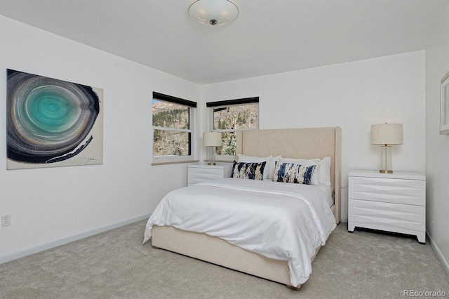 bedroom with baseboards and light colored carpet