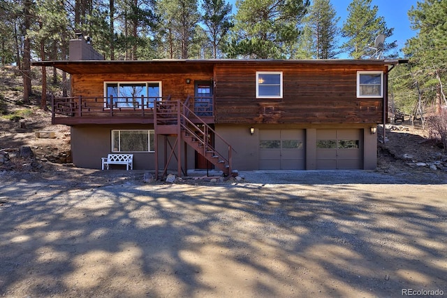 chalet / cabin with a chimney, a garage, stairway, stucco siding, and driveway