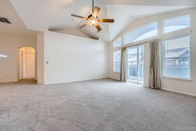 empty room with high vaulted ceiling, visible vents, arched walkways, and carpet flooring