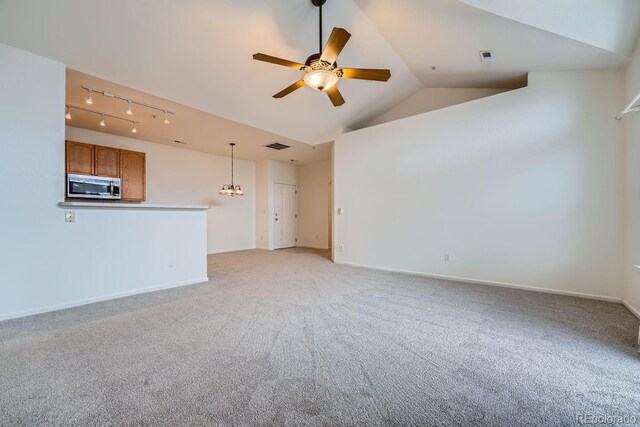 unfurnished living room featuring visible vents, light carpet, vaulted ceiling, baseboards, and ceiling fan with notable chandelier