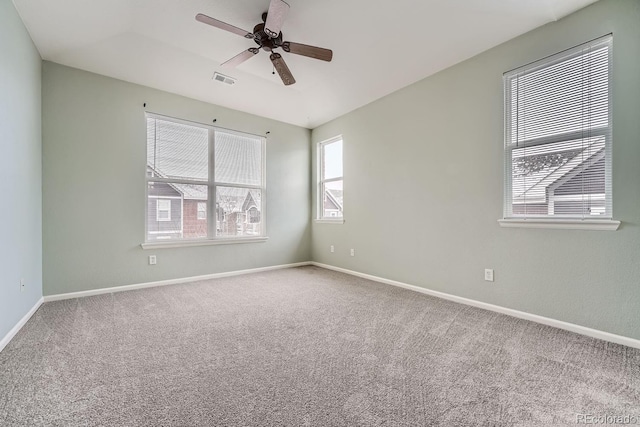 carpeted empty room with visible vents, ceiling fan, and baseboards