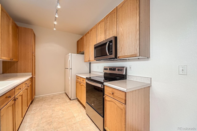 kitchen with track lighting, baseboards, stainless steel appliances, and light countertops