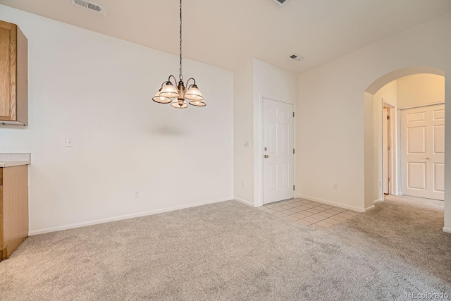 empty room featuring arched walkways, light colored carpet, visible vents, a chandelier, and baseboards