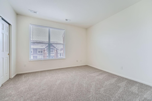 carpeted spare room featuring baseboards and visible vents