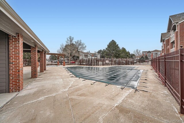 community pool with a patio area and fence