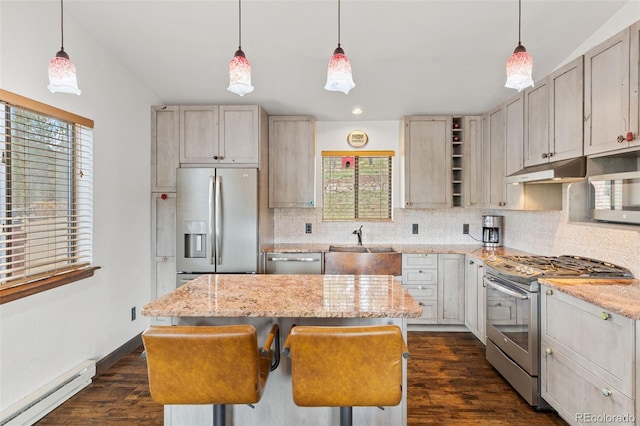 kitchen with backsplash, baseboard heating, a sink, under cabinet range hood, and stainless steel appliances
