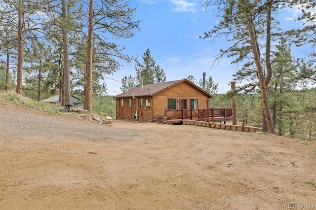 exterior space featuring a wooden deck and dirt driveway