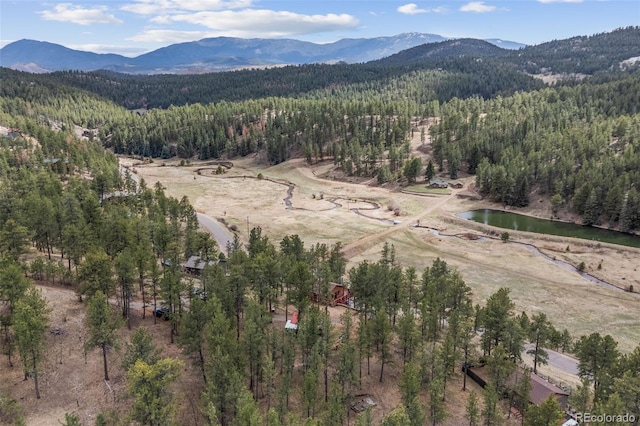 drone / aerial view featuring a water and mountain view and a view of trees