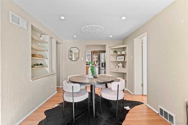 dining area with light hardwood / wood-style floors and built in features