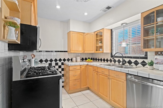 kitchen with light tile patterned flooring, appliances with stainless steel finishes, tile countertops, sink, and light brown cabinets