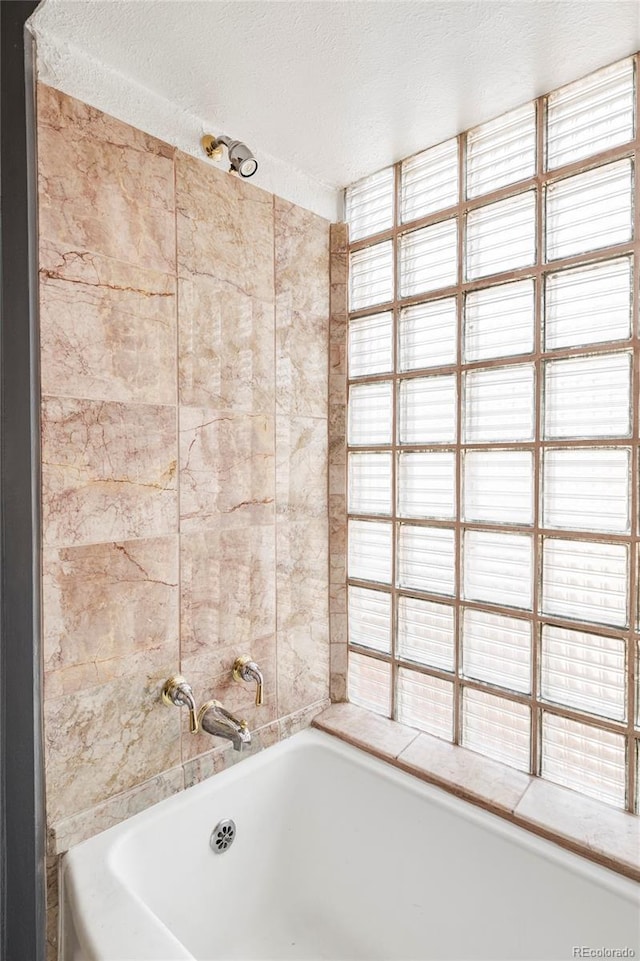 full bathroom featuring a bath and a textured ceiling