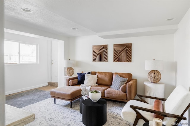 living area featuring a textured ceiling and baseboards