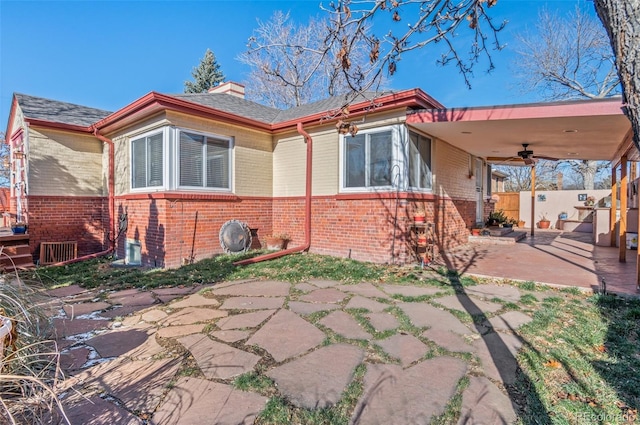 back of house featuring fence, an attached carport, ceiling fan, brick siding, and a patio area