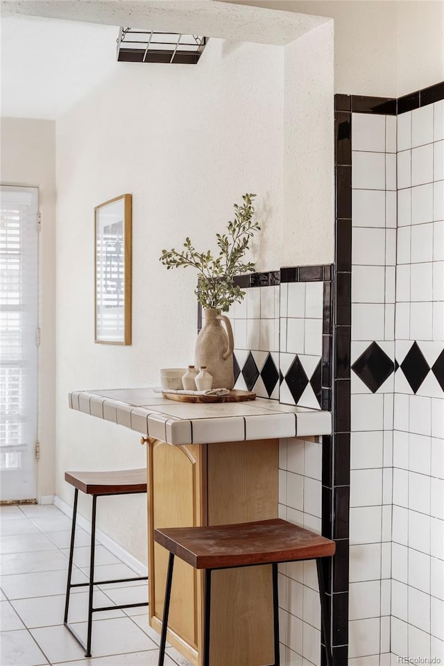 interior space featuring light tile patterned flooring, tile countertops, and baseboards