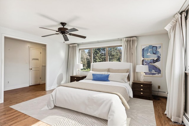 bedroom with baseboard heating, wood-type flooring, and ceiling fan