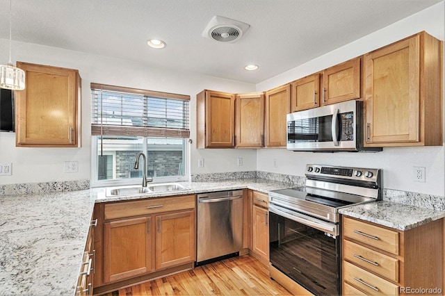 24285 E Wagon Trail Ave, Aurora, CO 80016 - kitchen with stainless steel appliances, a sink, light wood-style flooring, light stone counters, and recessed lighting