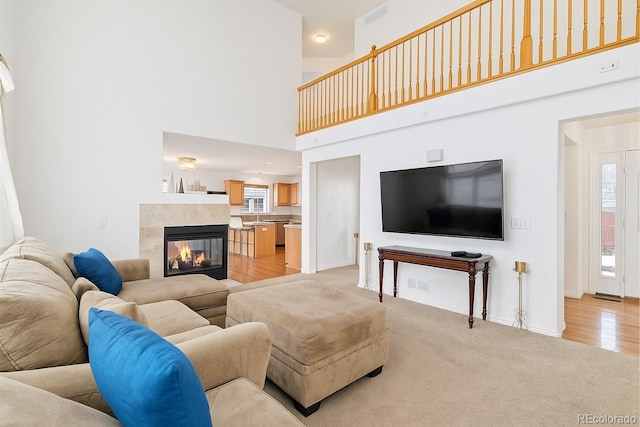 24285 E Wagon Trail Ave, Aurora, CO 80016 - living area featuring a high ceiling, baseboards, light colored carpet, and a tile fireplace