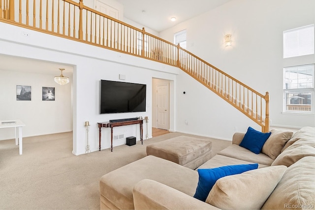 24285 E Wagon Trail Ave, Aurora, CO 80016 - carpeted living room featuring a towering ceiling, stairs, and baseboards