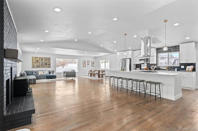 kitchen with stainless steel fridge, a spacious island, a fireplace, and a wealth of natural light