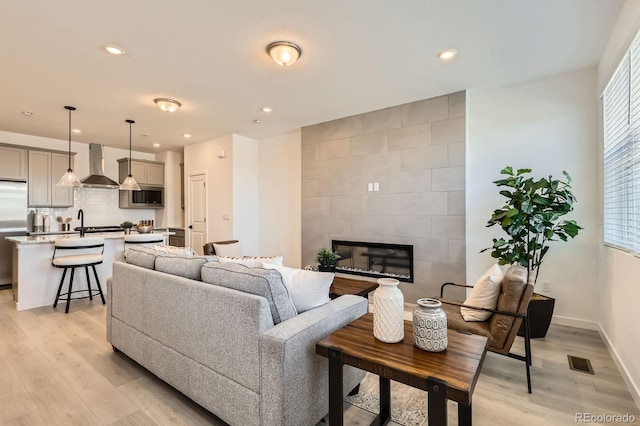 374 N Geneva, Aurora, CO 80010 - living room featuring light wood-style flooring, a tile fireplace, recessed lighting, and baseboards